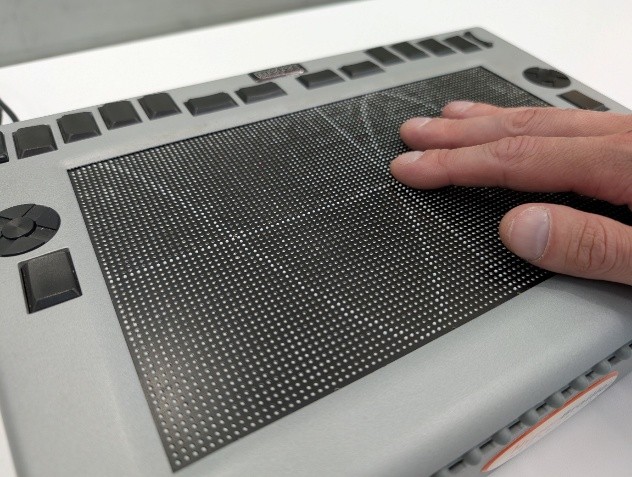 Hand berührt eine Braille-Tablet-Oberfläche zur Blindenschrift-Interaktion.